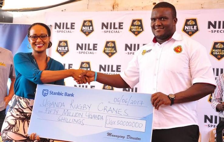 Stanbic Senior Marketing Manager Sonia Karamagi hands over a cheque worth Ugx 50 million to Uganda Rugby Cranes Captain Brian Odongo.