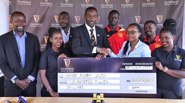 Uganda Breweries Head of Beer, Estella Muzito hands over a dummy cheque to Michael Wandera, the manager of the Uganda National 7s team.
