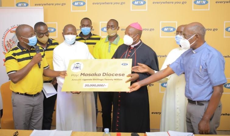 MTN's Joseph Bogera hands over a cheque to His Grace, Bishop Serverus Jjumba to support the Martyrs Day preparations.