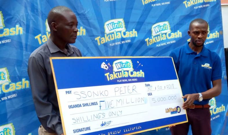 Peter Ssonko receives a dummy cheque from Takula Cash's Paul Sekantuuka.