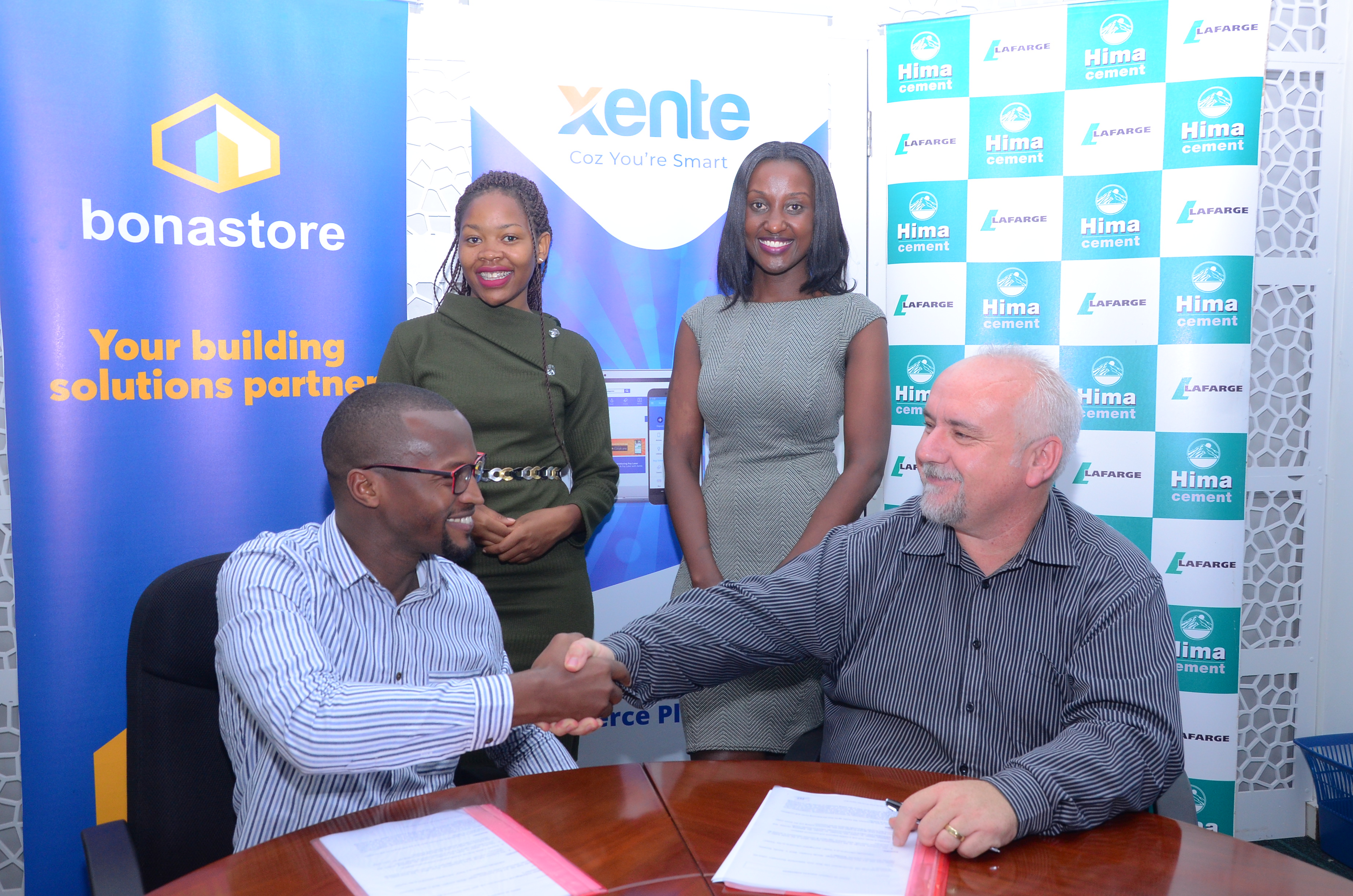 Francis Nkurunungi, Xente's Chief Operations Officer (Seated L) and Paul Bernard Kelly (Seated R), Hima Cement's Retail Manager sign an MoU to open an online shopping platform.