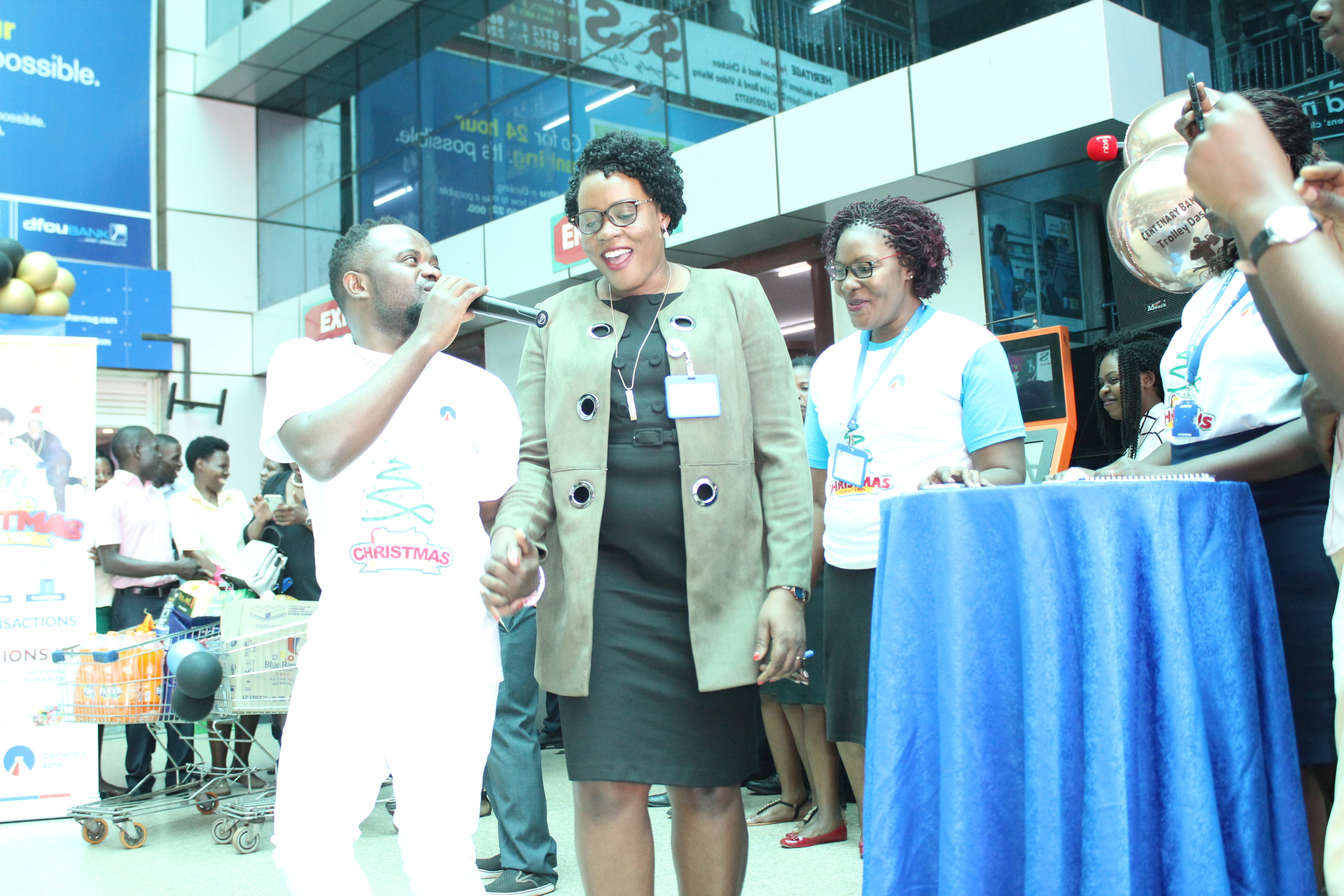 Mrs. Beatrice Lugalambi (C), General Manager Corporate Communications and Marketing at Centenary Bank shares alight moment with David Lutalo. This was at Capital Shoppers Ntinda during the official launch of Centenary Banks' Cente Christamss promo.