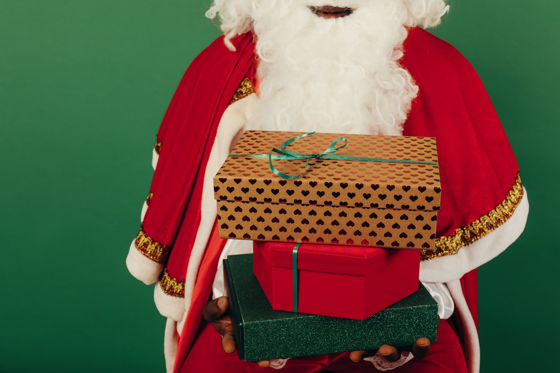 person wearing santa claus outfit while holding christmas gifts